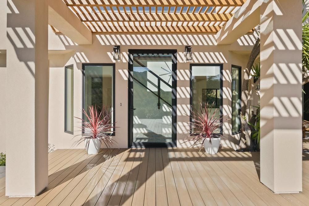 The front of a house with a wooden deck and a pergola