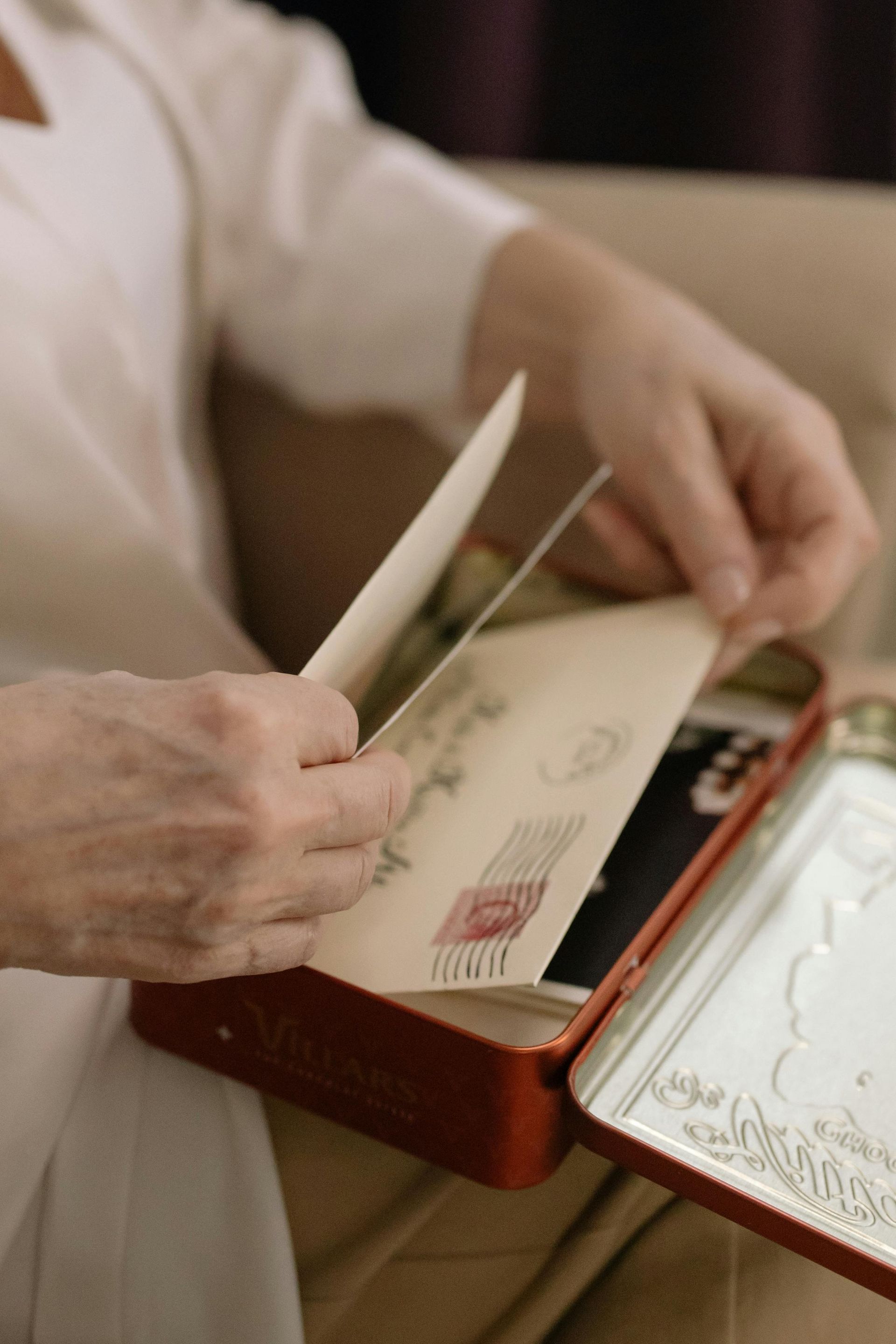 A woman is holding an envelope in a red tin