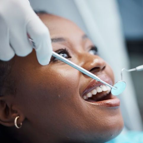 A woman is getting her teeth examined by a dentist.