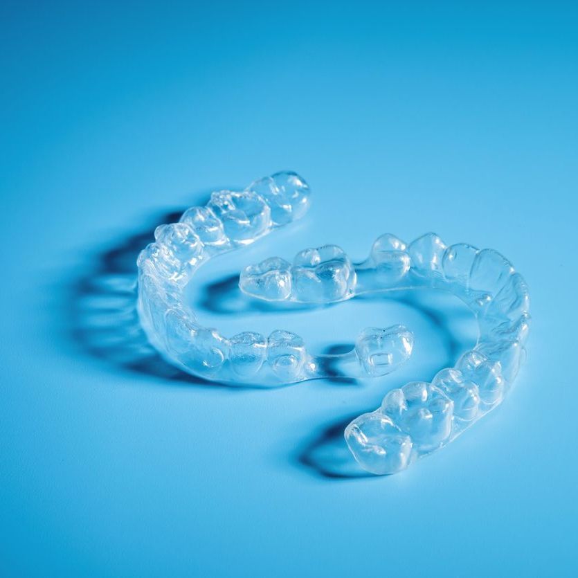 A clear mouth guard is sitting on a blue surface.