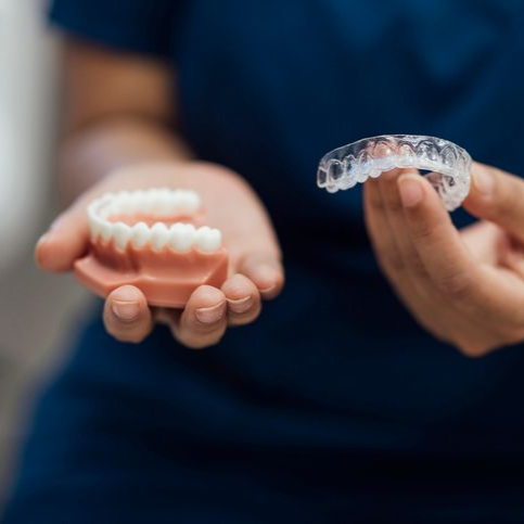 A woman is brushing her teeth in front of a mirror.