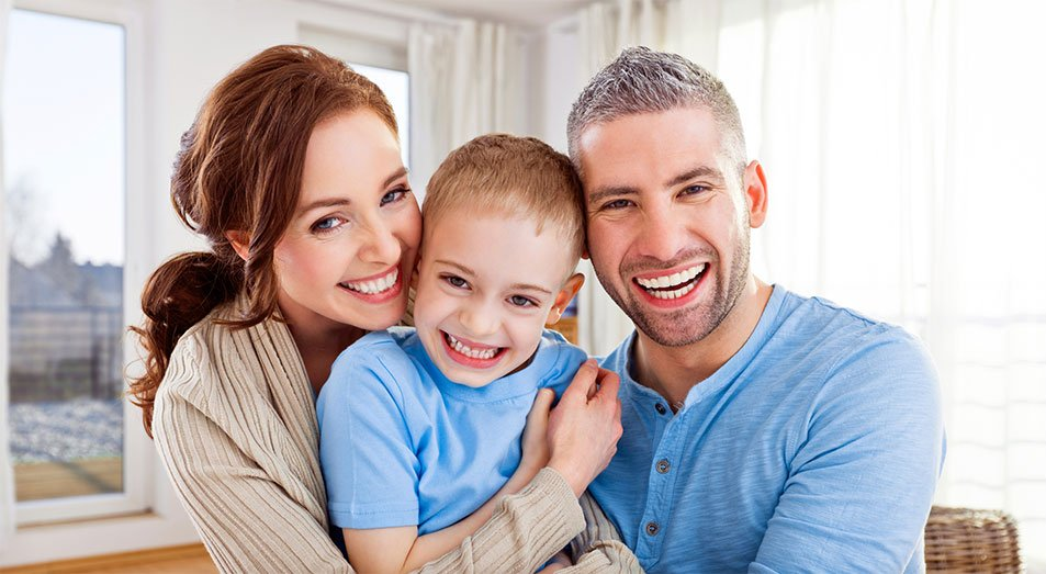 A family is posing for a picture together in a living room.
