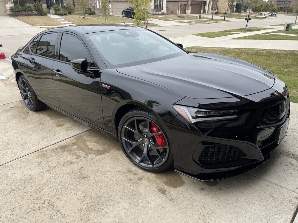 Black Acura TLX Type S sedan parked in a driveway, red brake calipers visible.