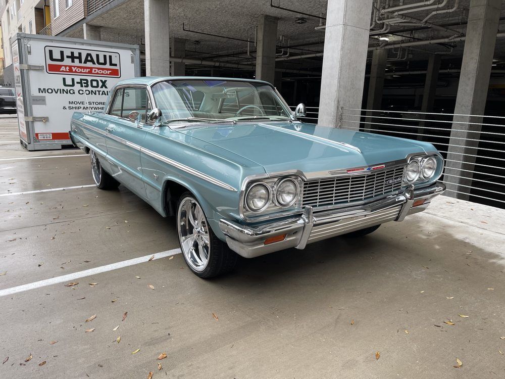 Two turquoise jet skis on a trailer in front of a brick wall. Each has red accents and TX license plates.