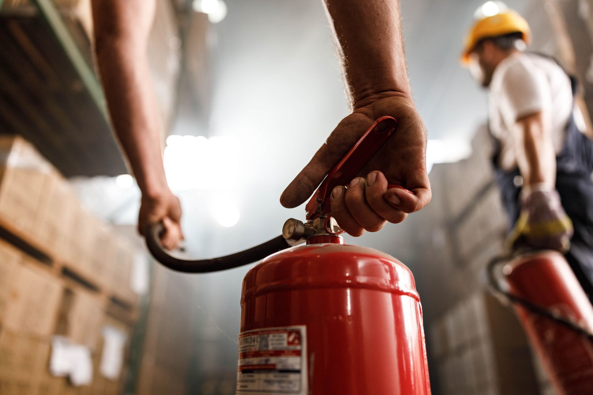 Man Using Fire Extinguisher in A Warehouse — Montrose, CO — Frontline Fire Defense