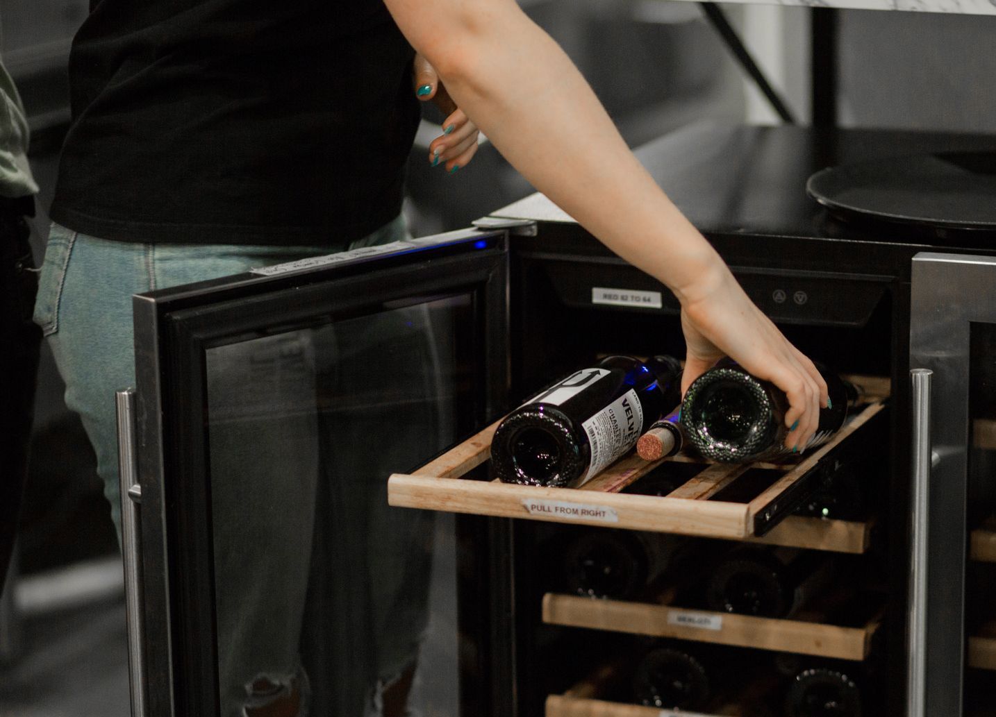 Wine Bottles being removed from a wine fridge