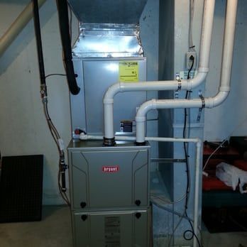 A Bryant brand furnace in a basement with white PVC pipes and black vent pipe.