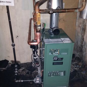 Green furnace with copper pipes in a basement setting.