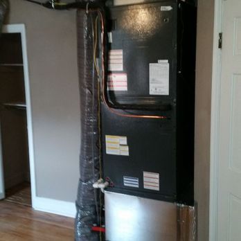 Black HVAC unit in a room, next to a duct and door frame.