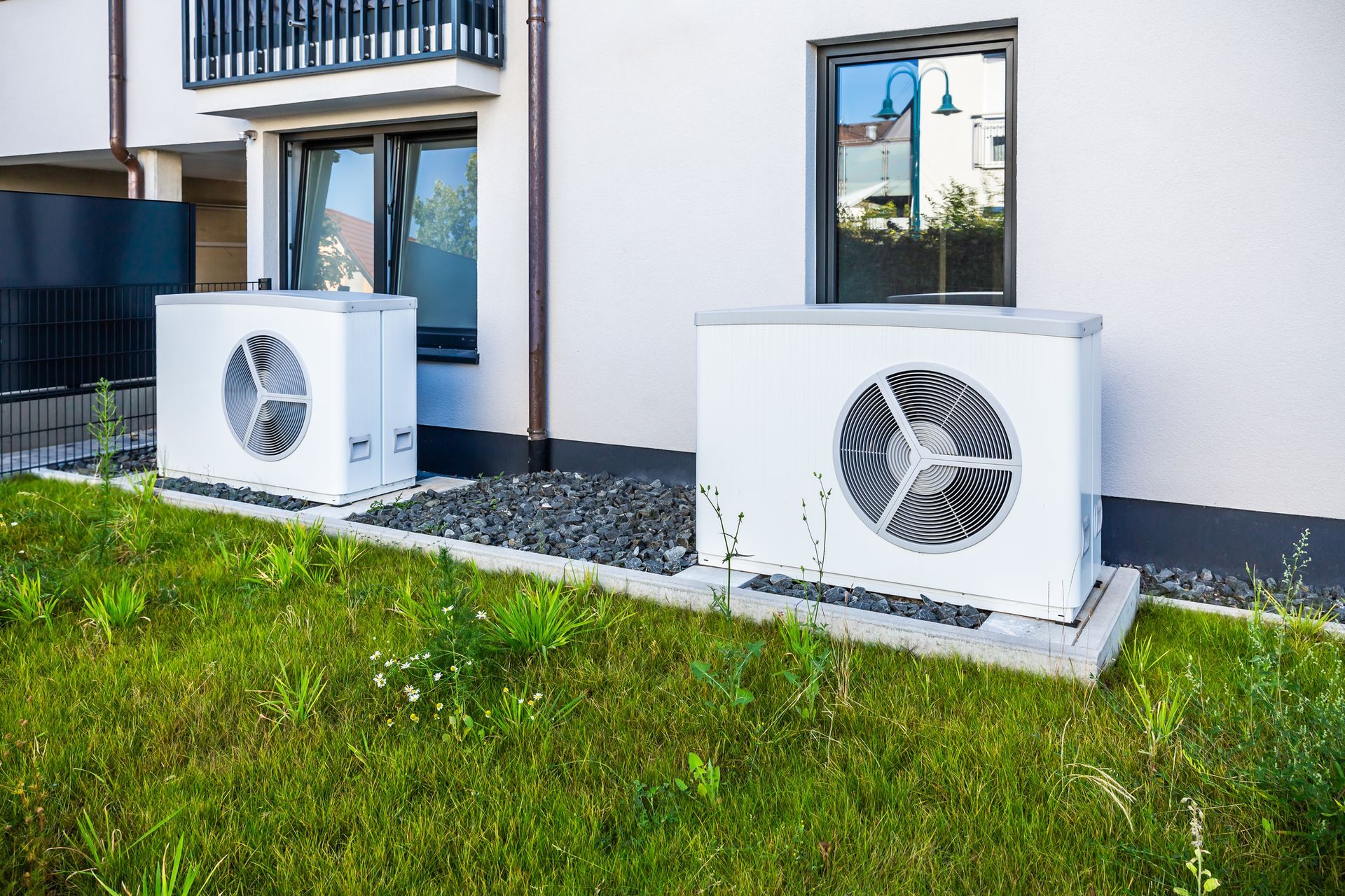 Two HVAC units are outside two windows in a modern home.