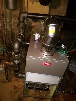 A Bryant furnace in a basement with metal ductwork and gas pipes.