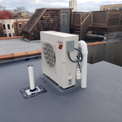 Rooftop with HVAC unit, white pipe, wooden stairs, and a door. Overcast day.