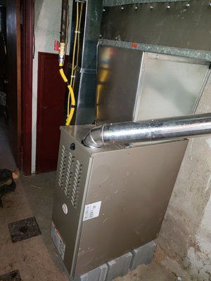 Furnace in a basement setting, with silver metal and yellow gas lines.