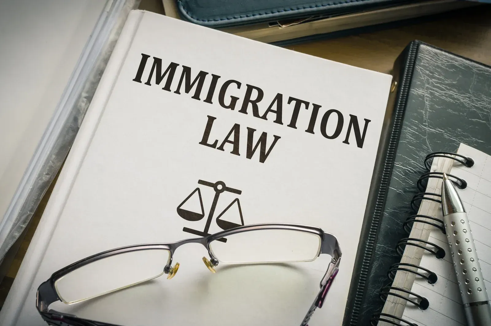 A book titled immigration law with glasses and scales of justice on it.