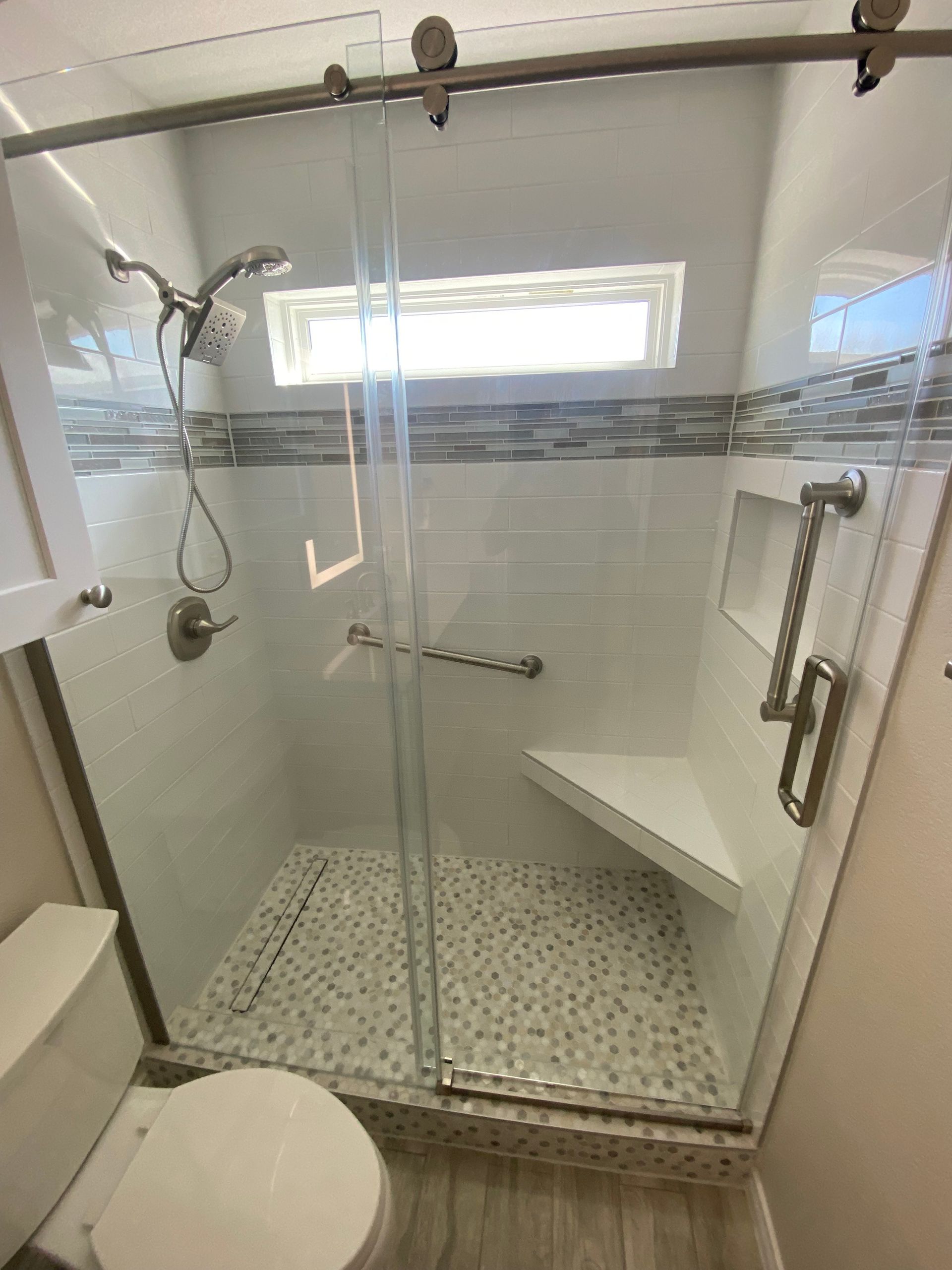 A bathroom with a toilet and a shower with a sliding glass door.