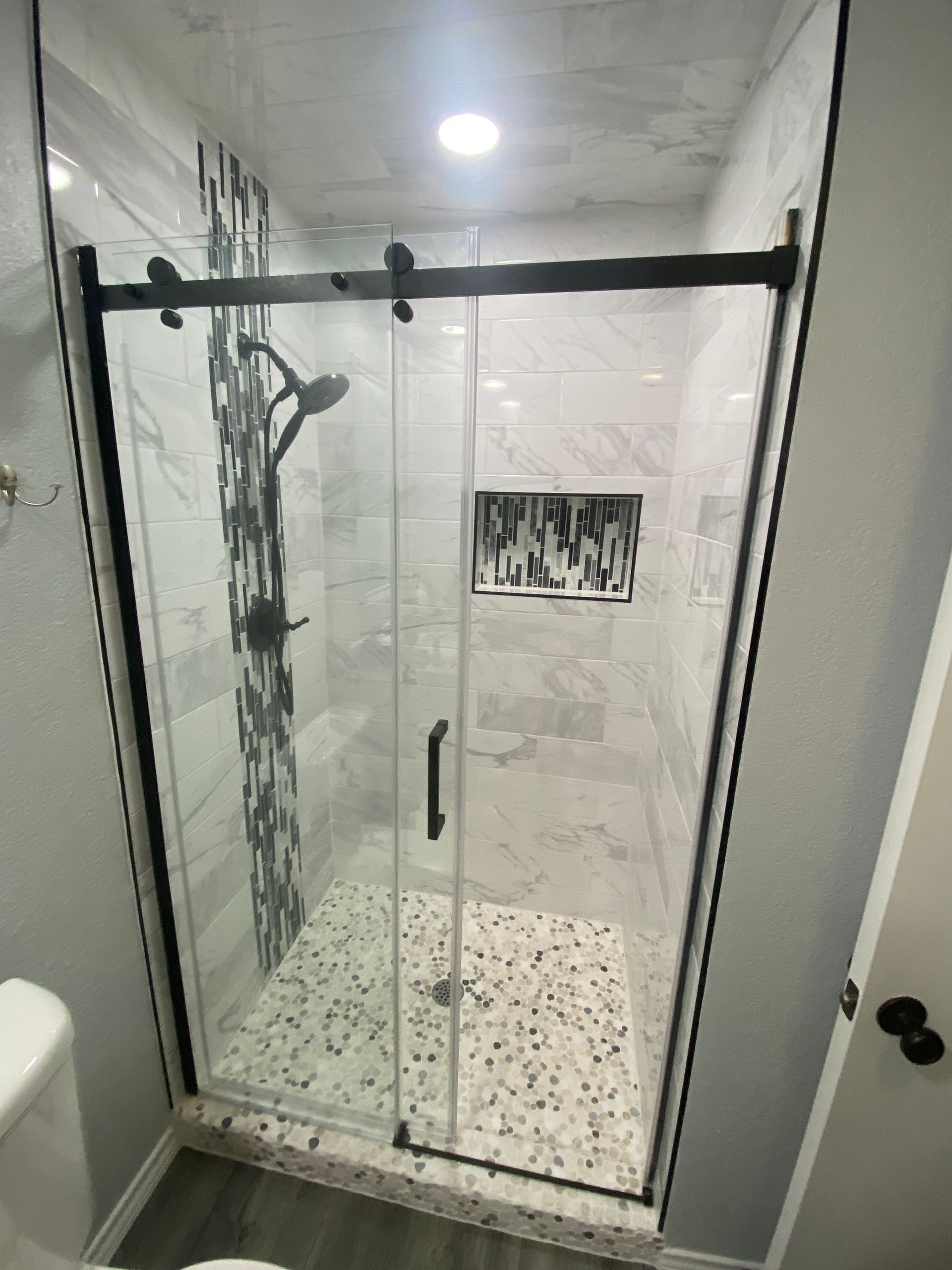 A bathroom with a walk in shower with a sliding glass door.