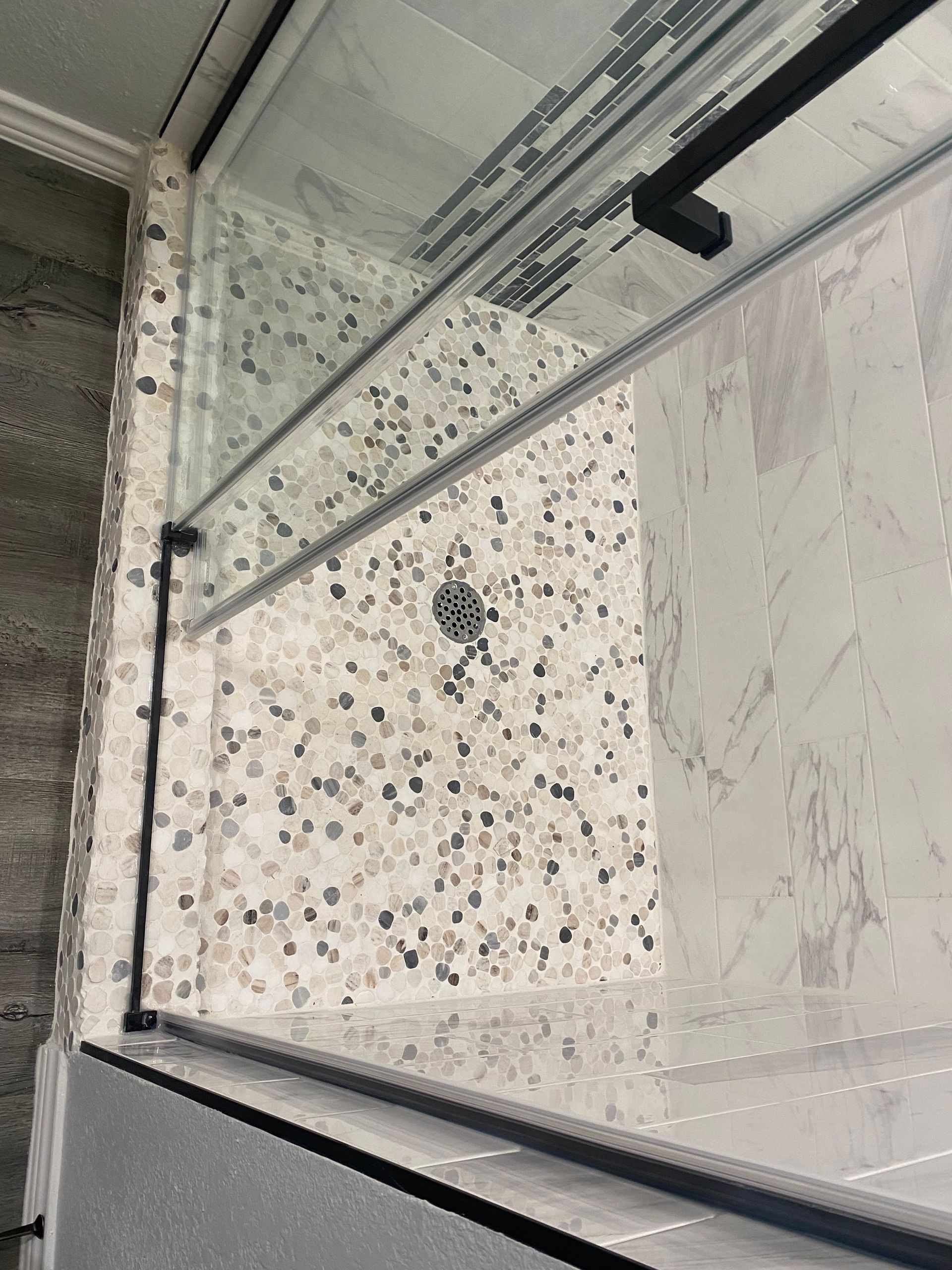 A shower stall with a sliding glass door in a bathroom.