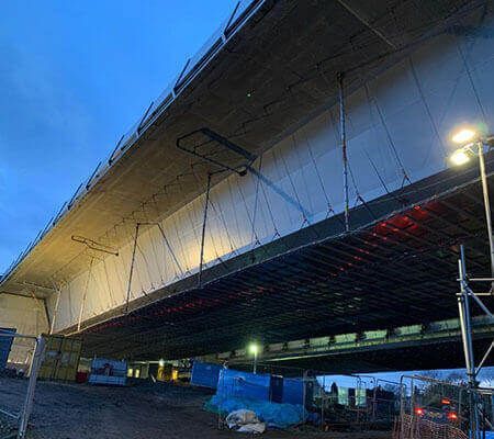 A bridge is being built over a road at night.