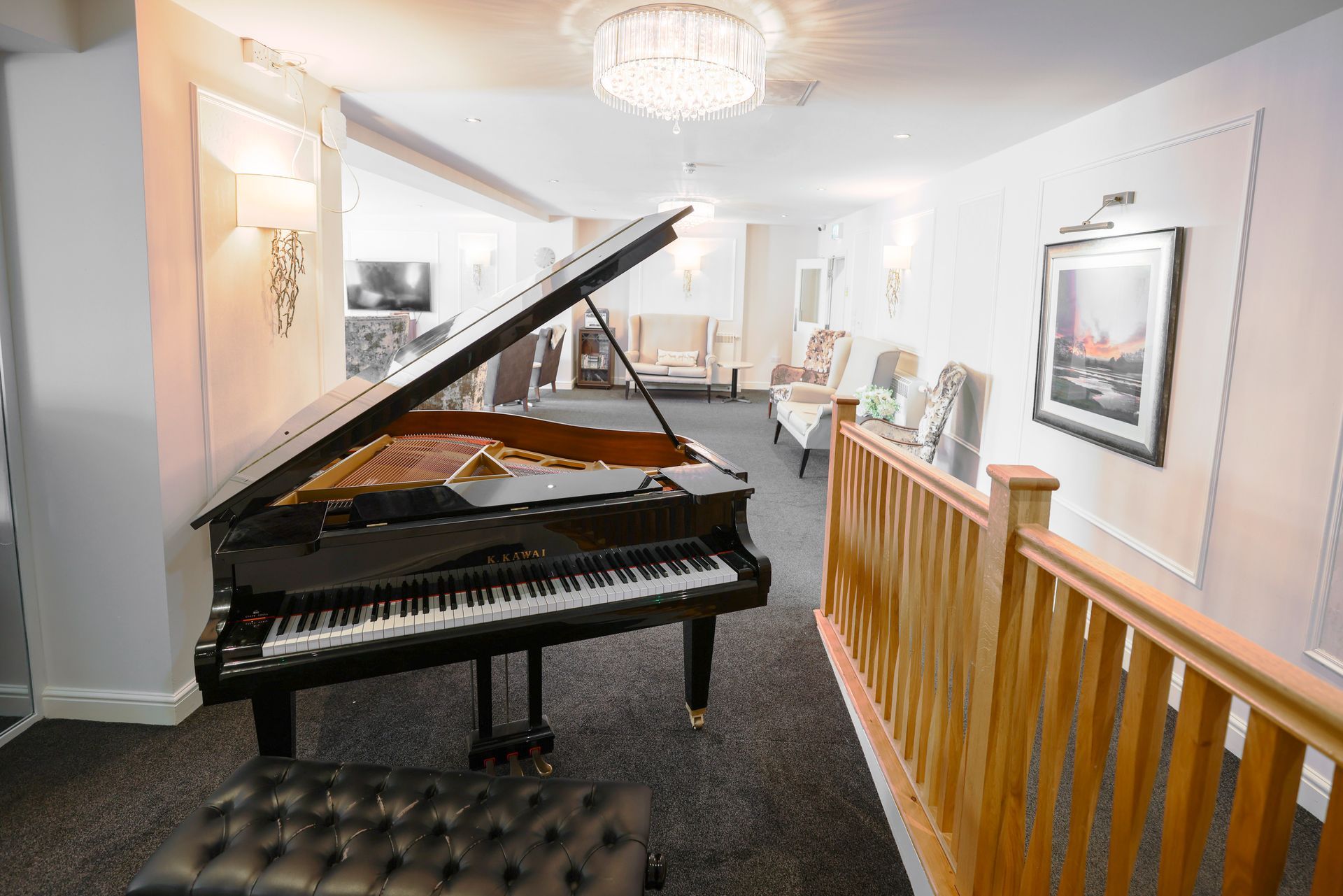 Grand piano in a bright hallway, with a staircase on the right and a fireplace visible in the background.