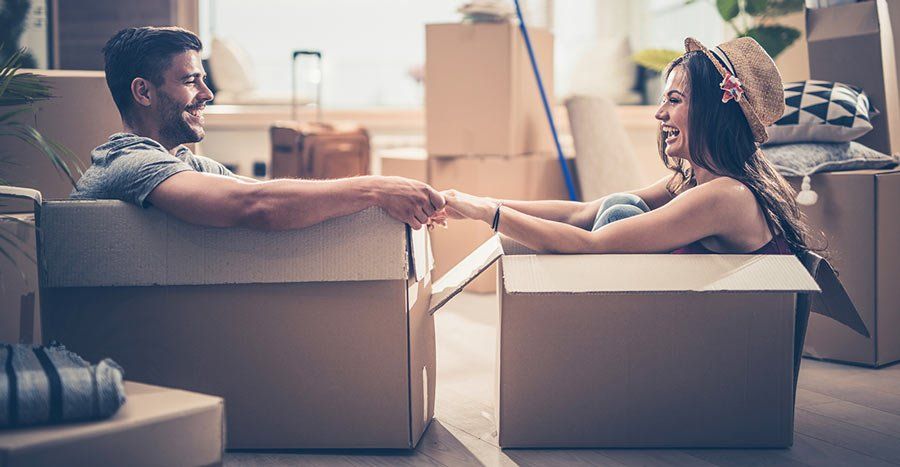 Man and woman sitting in move-in boxes on living room floor
