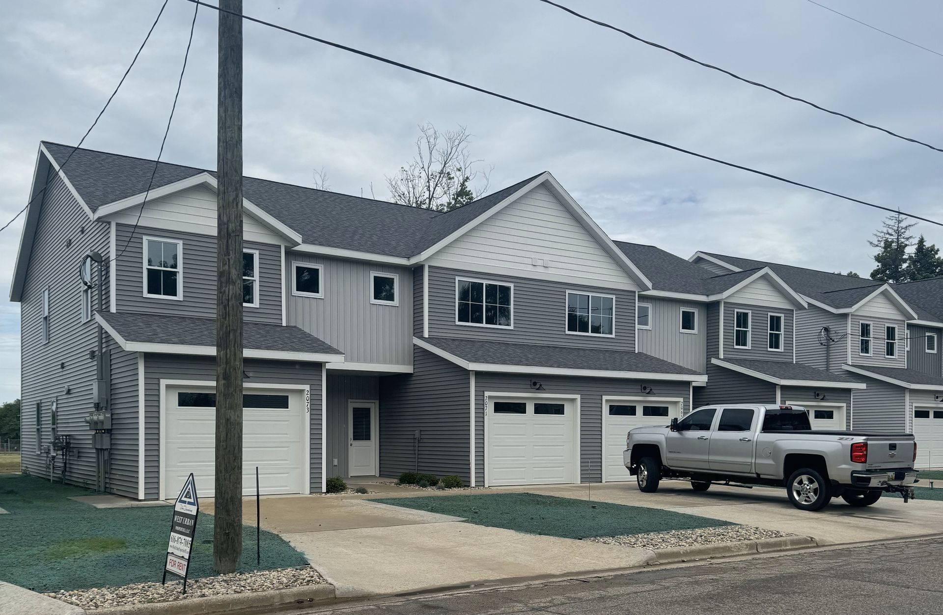 A silver truck is parked in front of a row of houses.