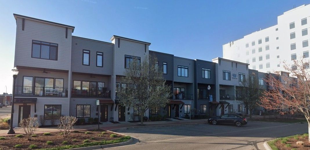 A row of apartment buildings with a large white building in the background.