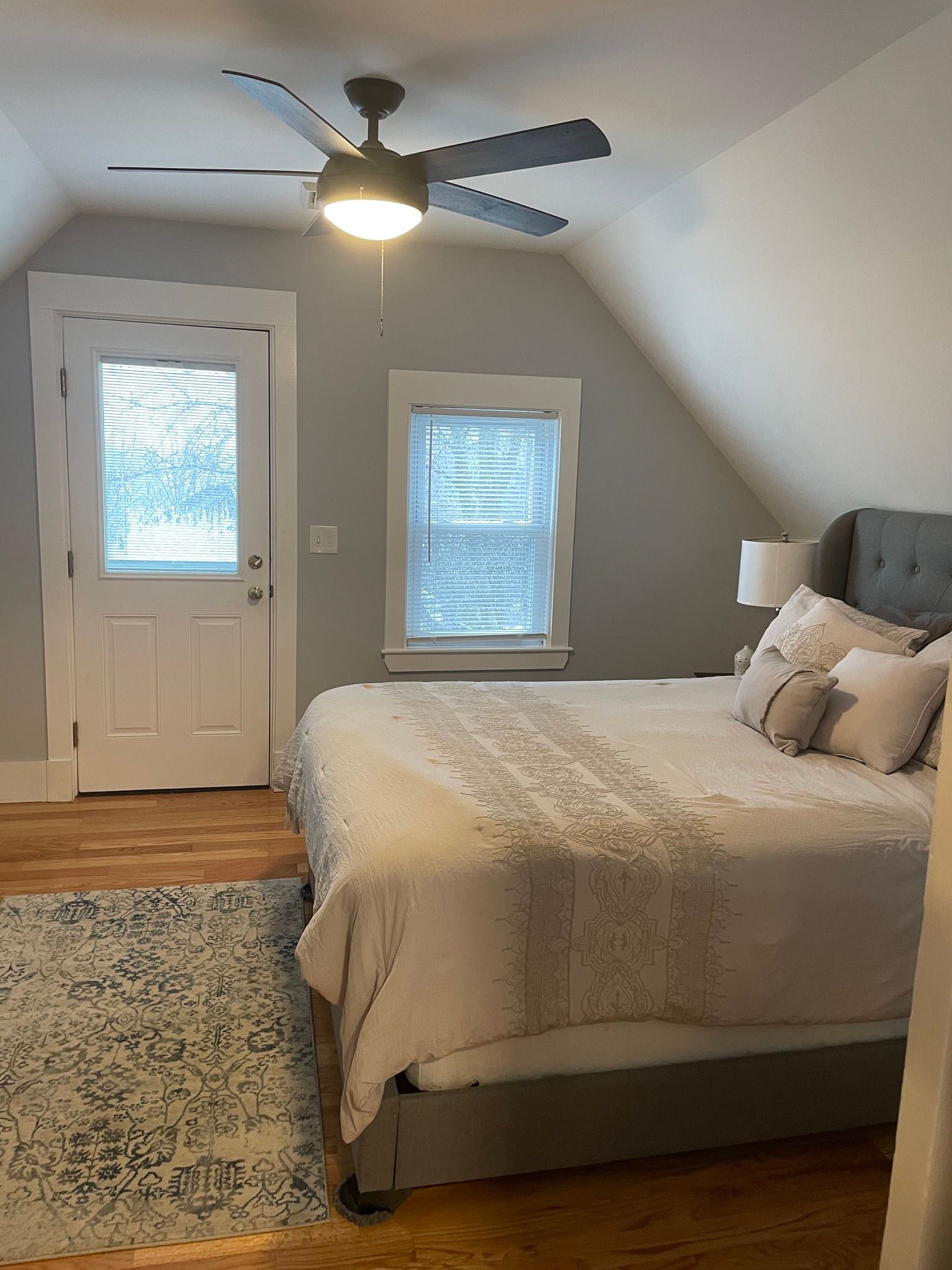 A bedroom with a bed , ceiling fan , and window.