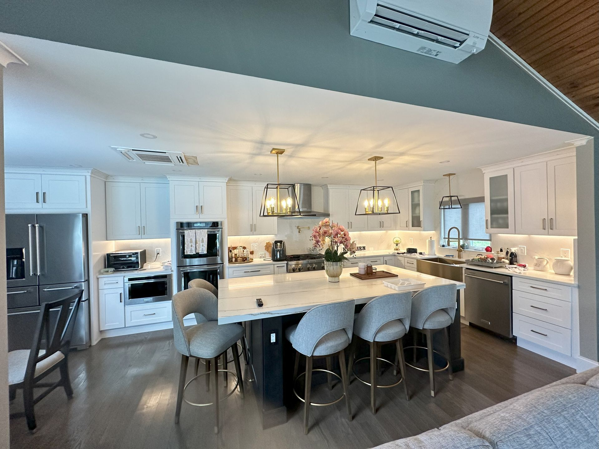 A kitchen with white cabinets and stainless steel appliances and a large island.