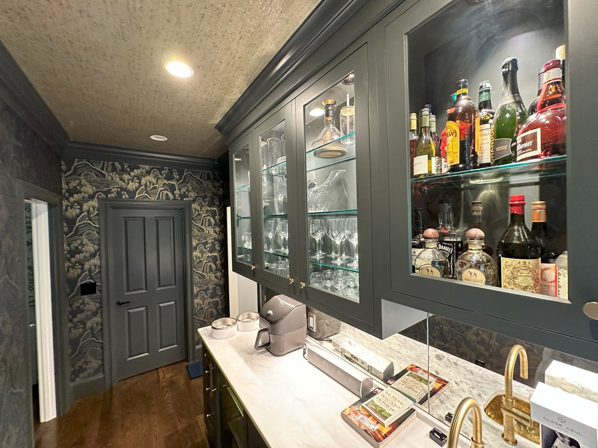 A kitchen with lots of bottles and glasses on shelves.
