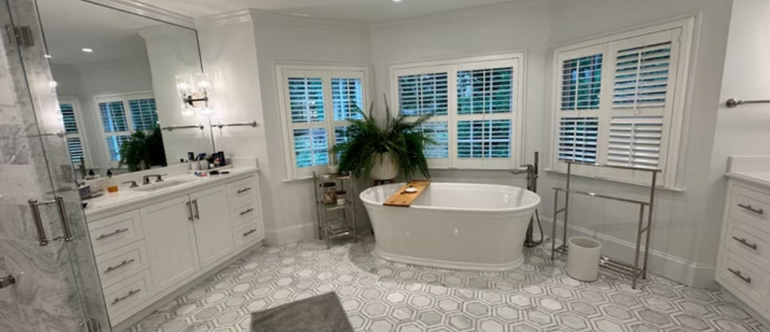 A bathroom with a tub , sink , mirror and window.