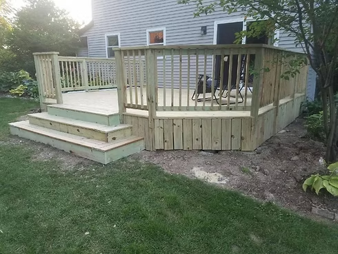 A wooden deck with stairs and a railing in front of a house.