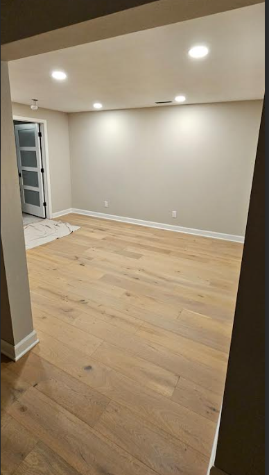 An empty room with hardwood floors and a door.