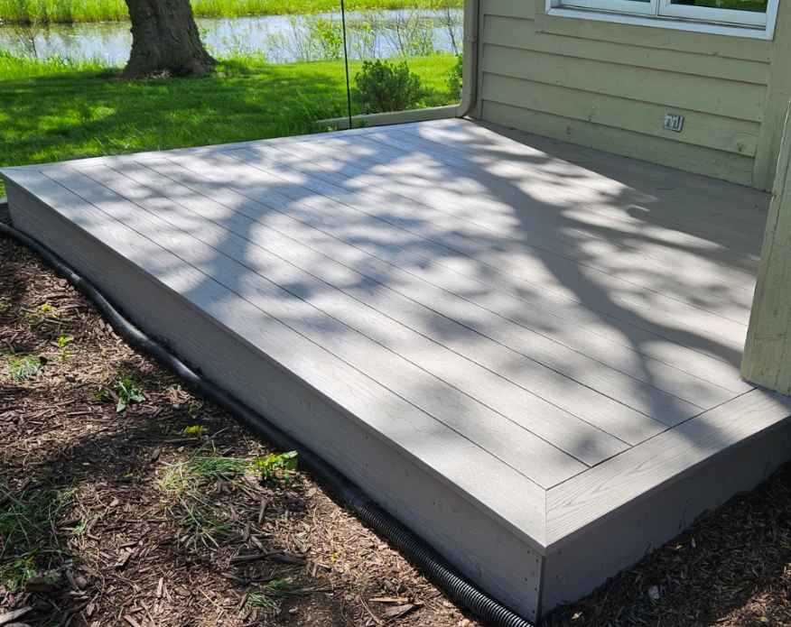 A gray deck is sitting in front of a house.