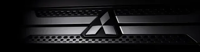 Imagem em close-up do logotipo preto da Mitsubishi em uma grade de carro escura e brilhante.
