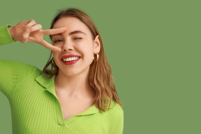 Close-up of smiling mouth while a dental shade guide selects a matching tooth color