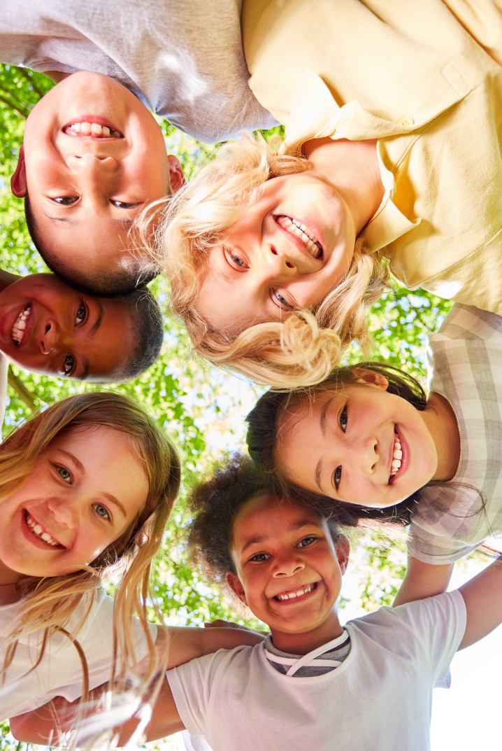 A group of children are standing in a circle and smiling.