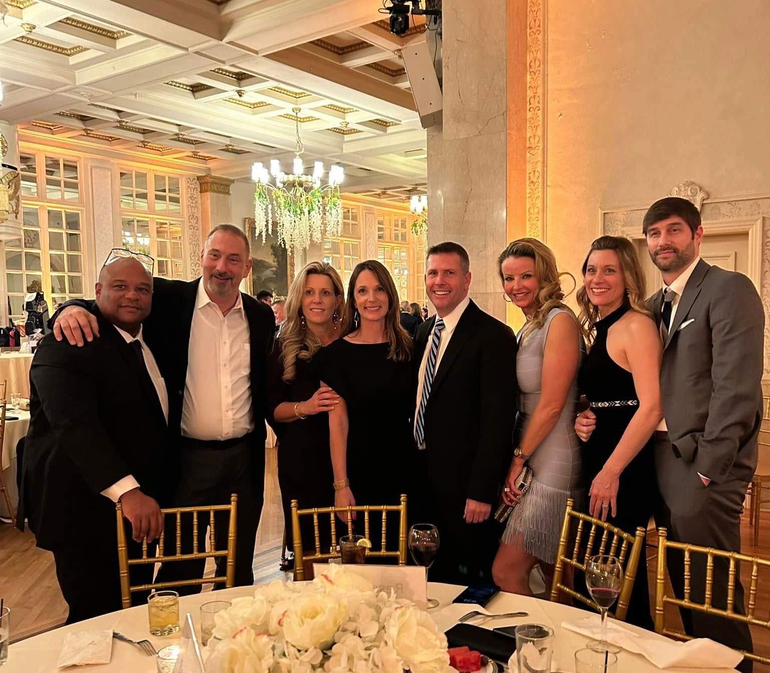 A group of people are posing for a picture at a fundraiser dining table.