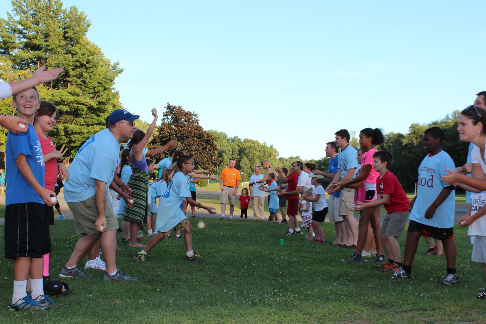 A group of adults and kids are playing a game in a field.