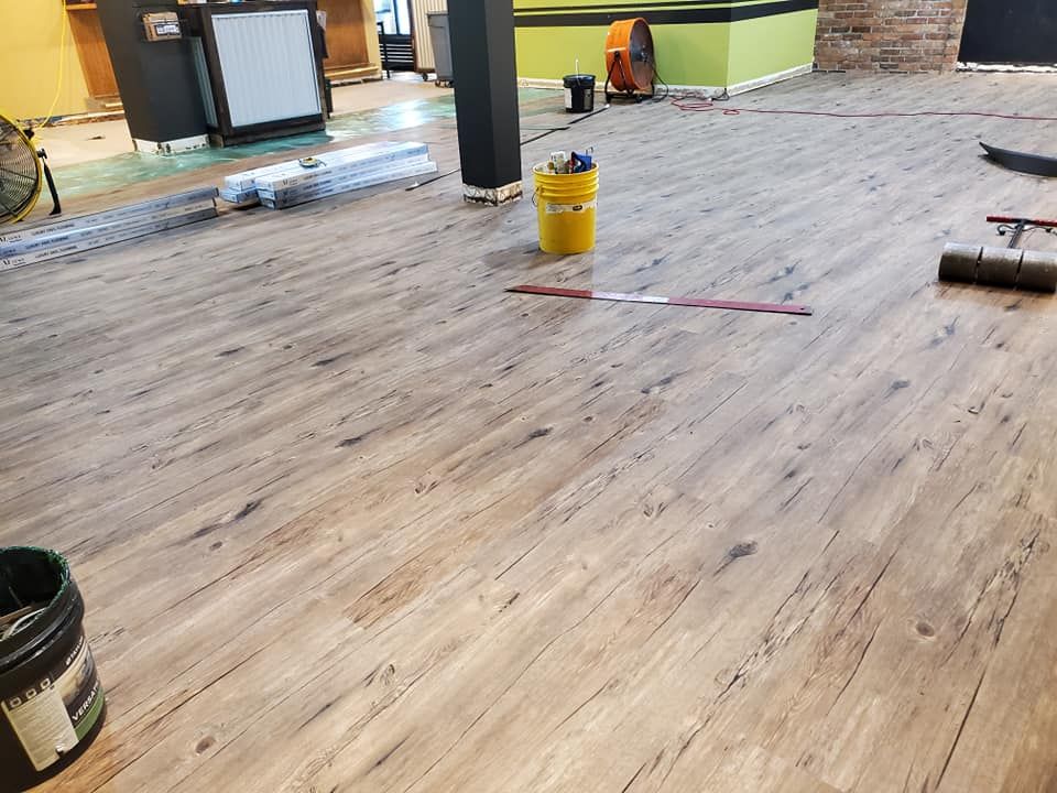 A yellow bucket is sitting on a wooden floor in a room.