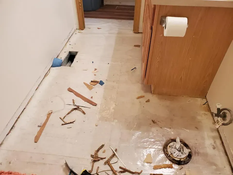 A bathroom with a toilet paper dispenser and a hammer on the floor.