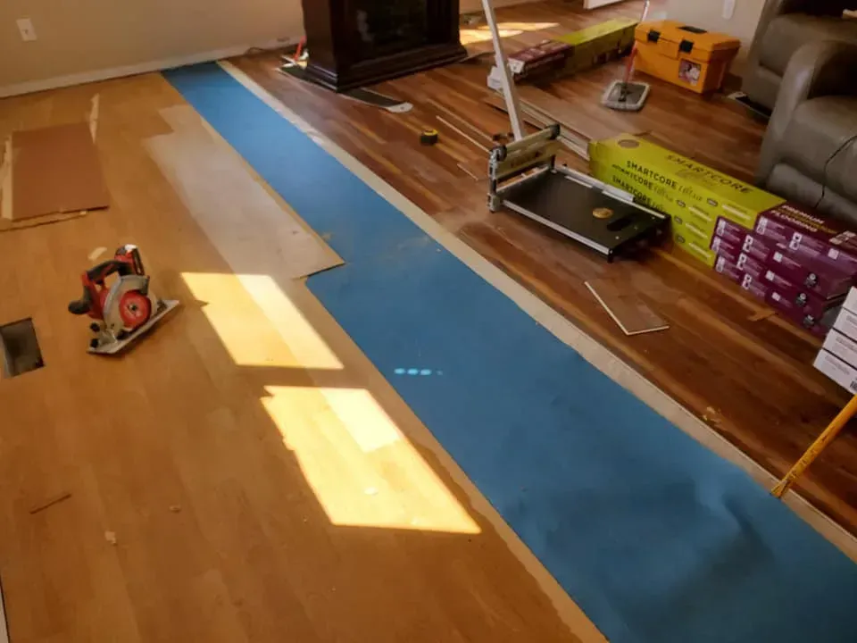 A wooden floor is being installed in a living room.