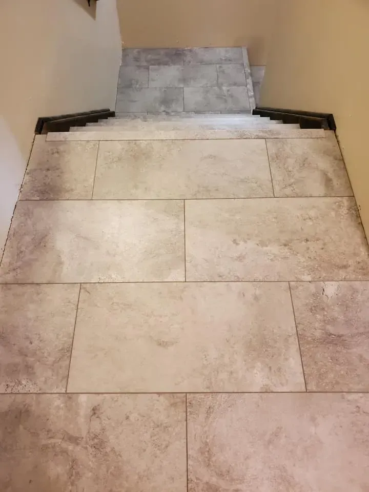 A close up of a tiled floor with stairs in the background.