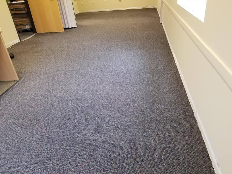 A long hallway with a gray carpet and white walls.