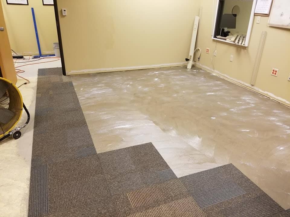 A room with a carpeted floor and a vacuum cleaner on the floor.