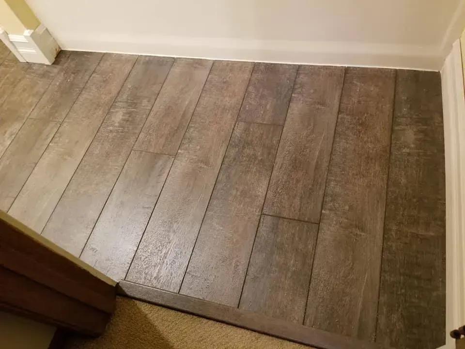A wooden floor in a room next to a door.