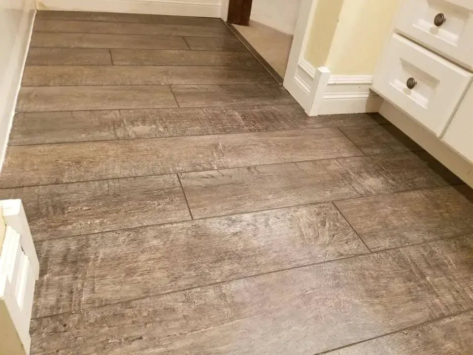 A bathroom with a wooden floor and white cabinets.