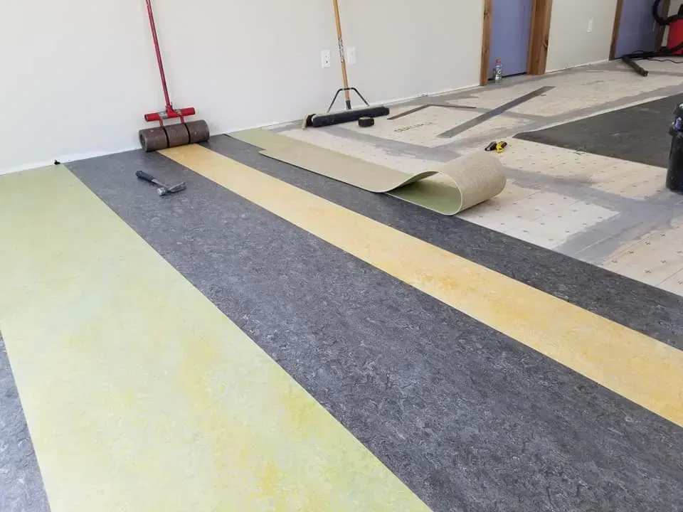 A roll of vinyl flooring is being installed in a room.