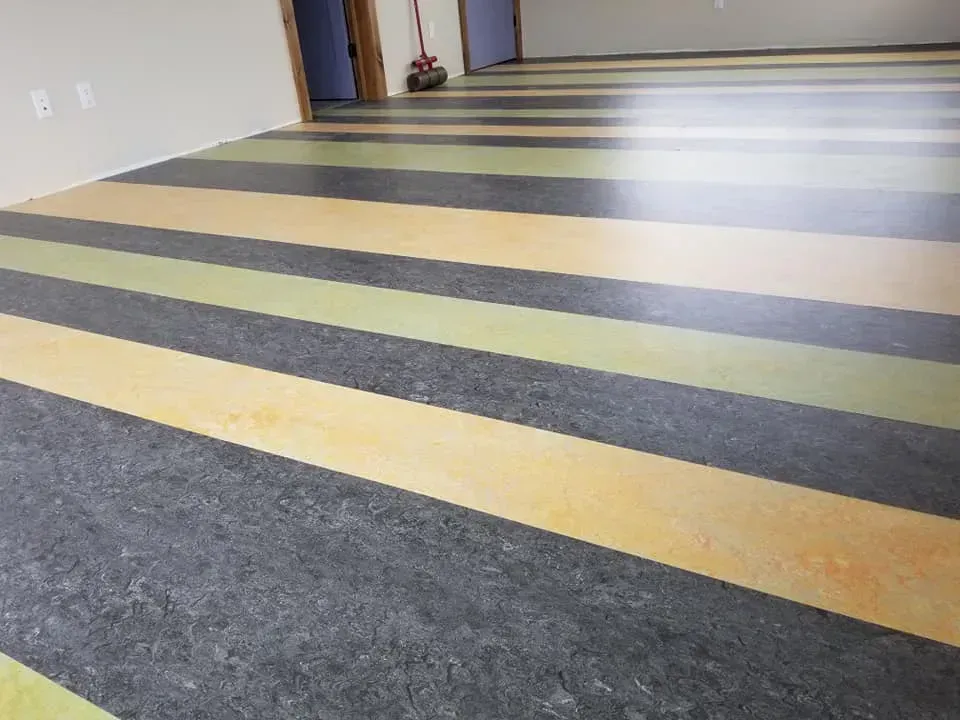 A room with a striped floor and a broom in the background