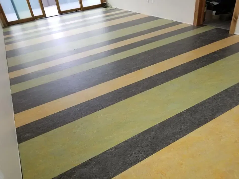 A striped floor in a room with a lot of windows.