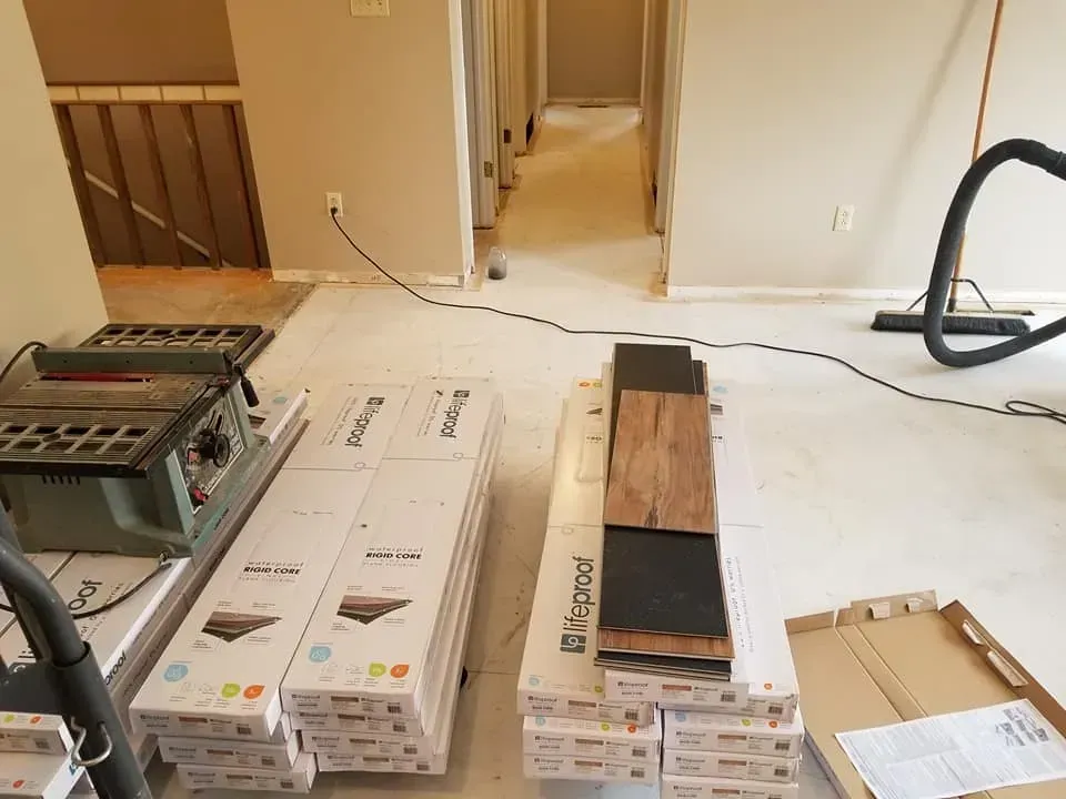 A vacuum cleaner is sitting on the floor next to a stack of wooden flooring.